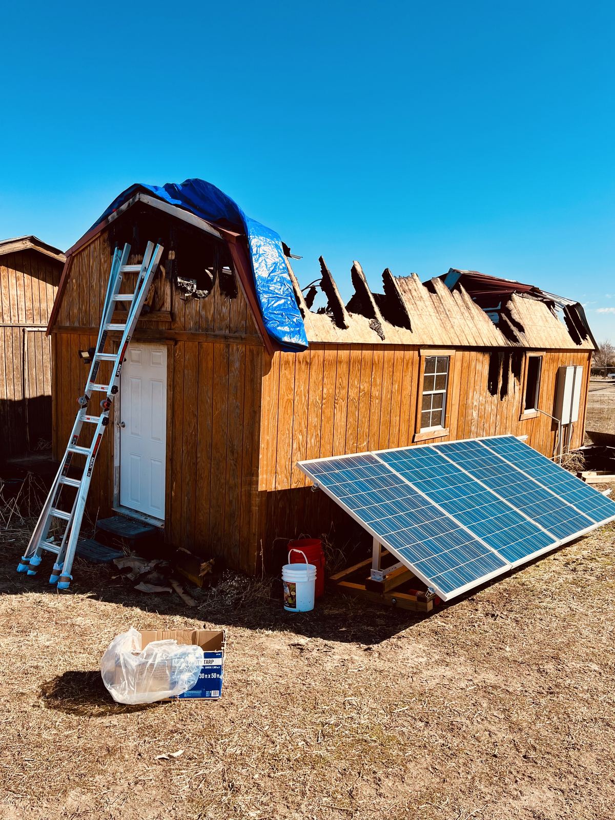 Installing emergency tarp on fire-damaged roof